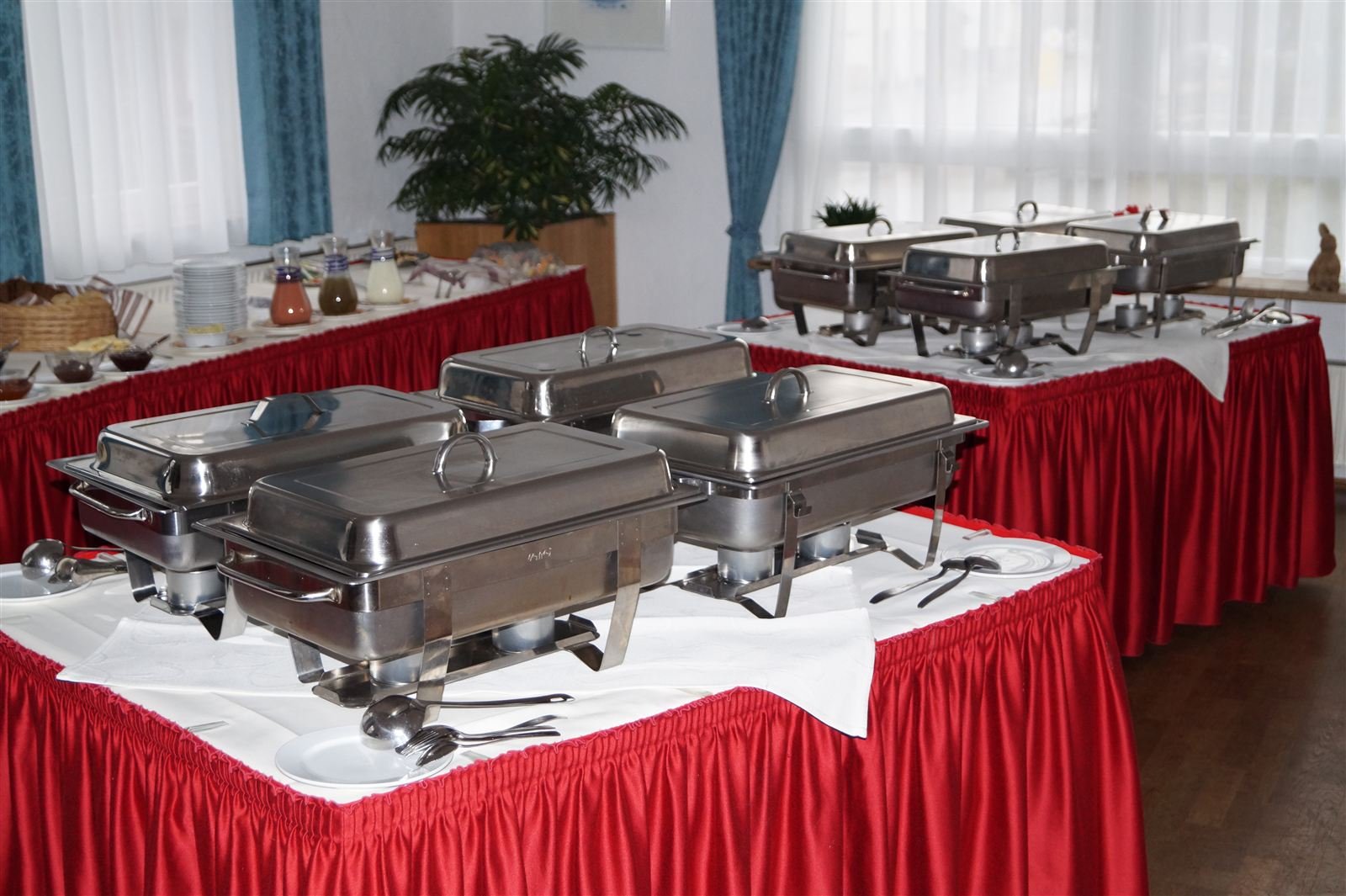 Buffet mit Warmhaltebehältern auf rot eingedeckten Tischen