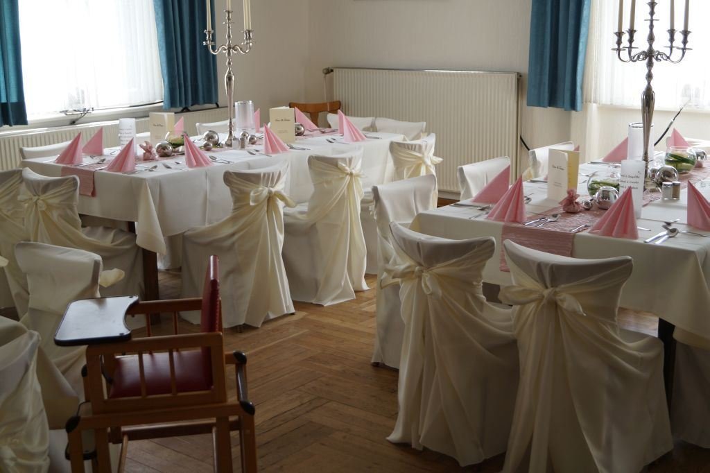 Saal mit weiß eingedeckten Tischen und Kerzenleuchter