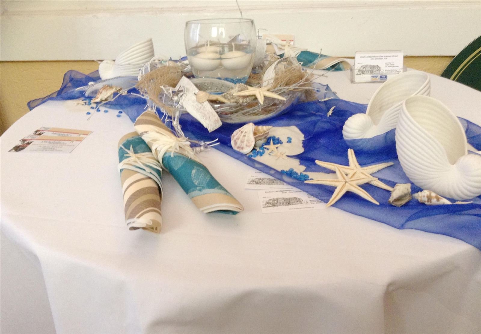 Maritime Tischdekoration mit Muscheln und Seesternen auf weißer Tafel