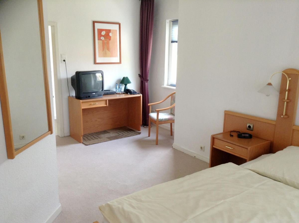 Helles Gästezimmer mit Schreibtisch, Fernseher und Bett